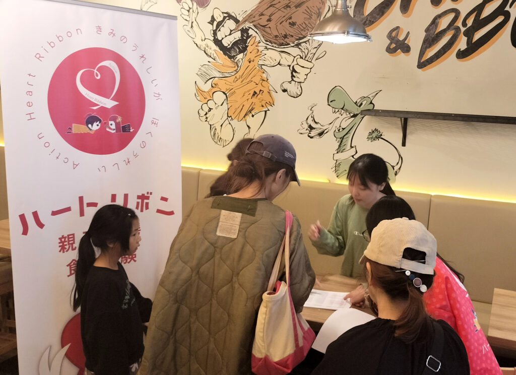 食料品の配布会場で、親子が受け取りの手続きをしている様子。
